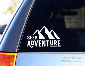 Photo of white vinyl decal of the phrase Seek Adventure with a mountain range symbol shown on SUV window ©Salt City Graphics